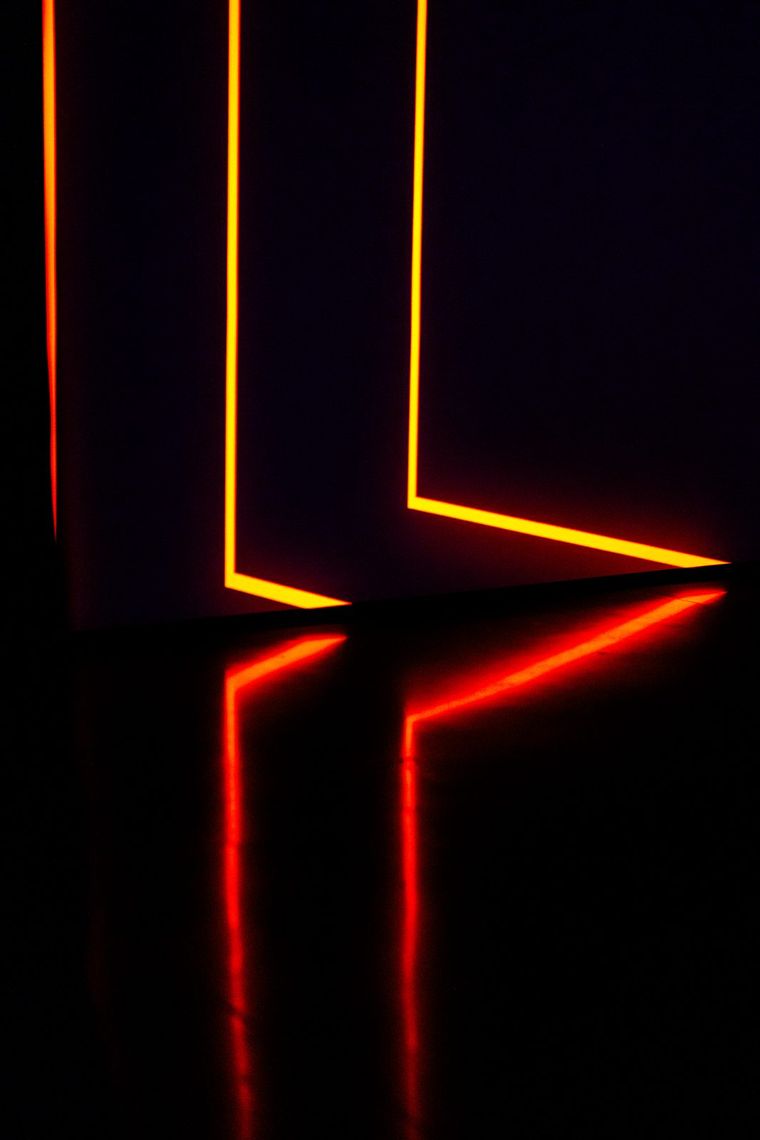Yellow and red lines of light bend along the walls of Onion Skin and reflect across the dark floor.