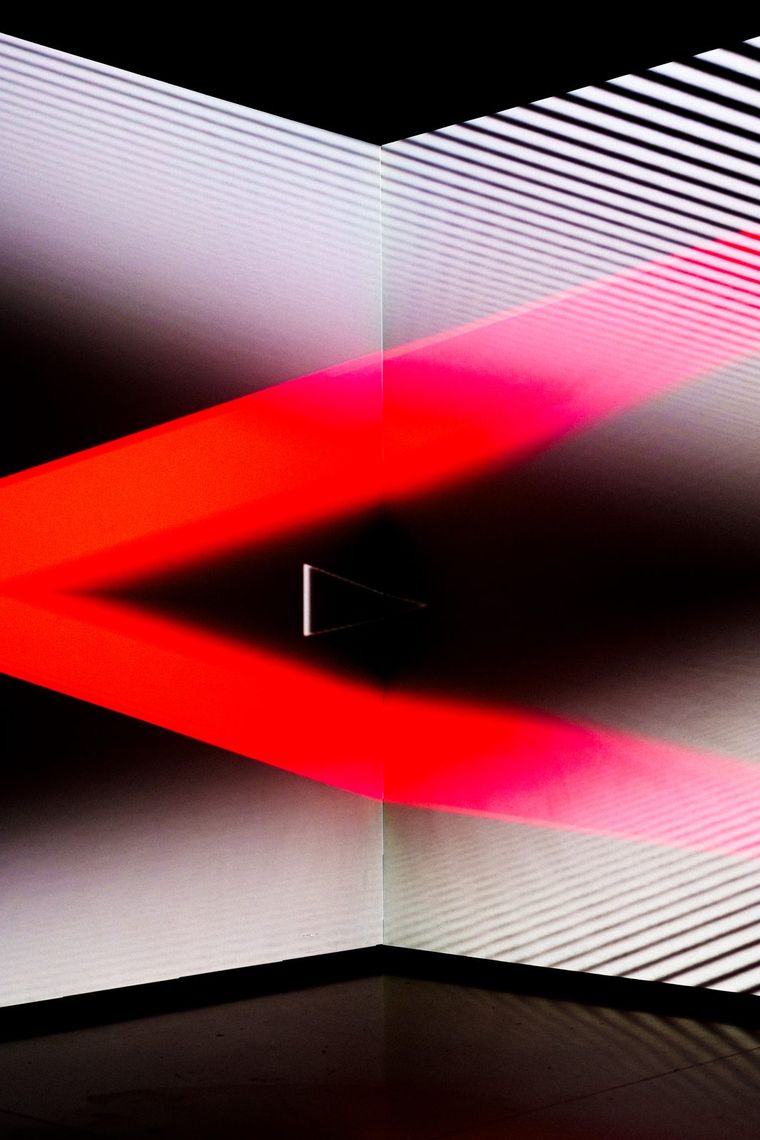 A band of red light cuts across white striped walls in Onion Skin, meeting at the corner.