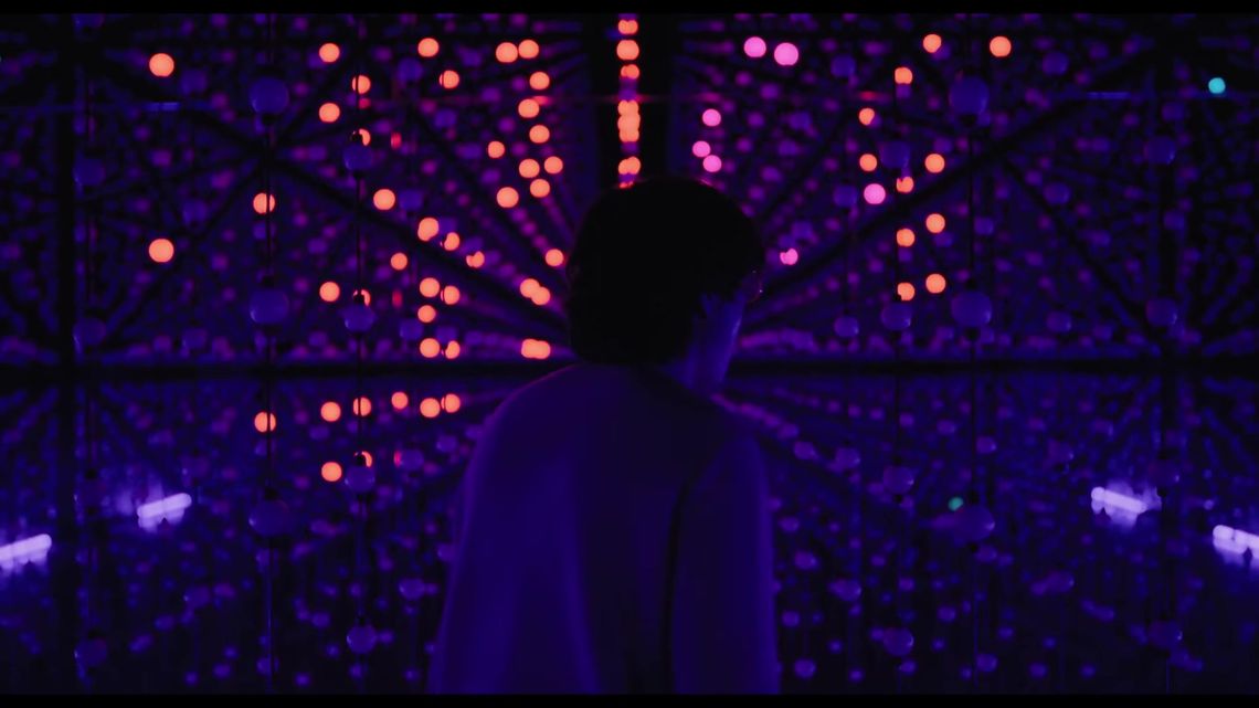 James Sweeney inside Unknown Atmospheres, surrounded by violet and pink suspended lights.