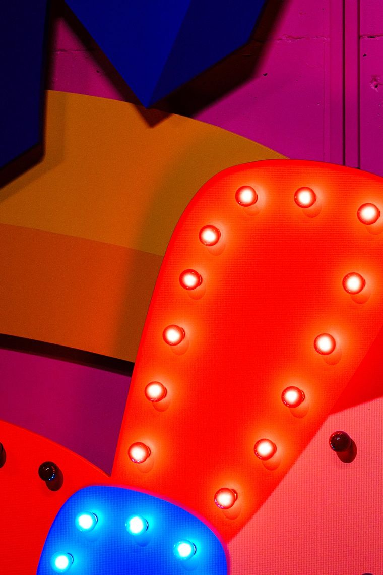 Close up of a red shape lined with glowing white bulbs beside a blue one, in Are You There?