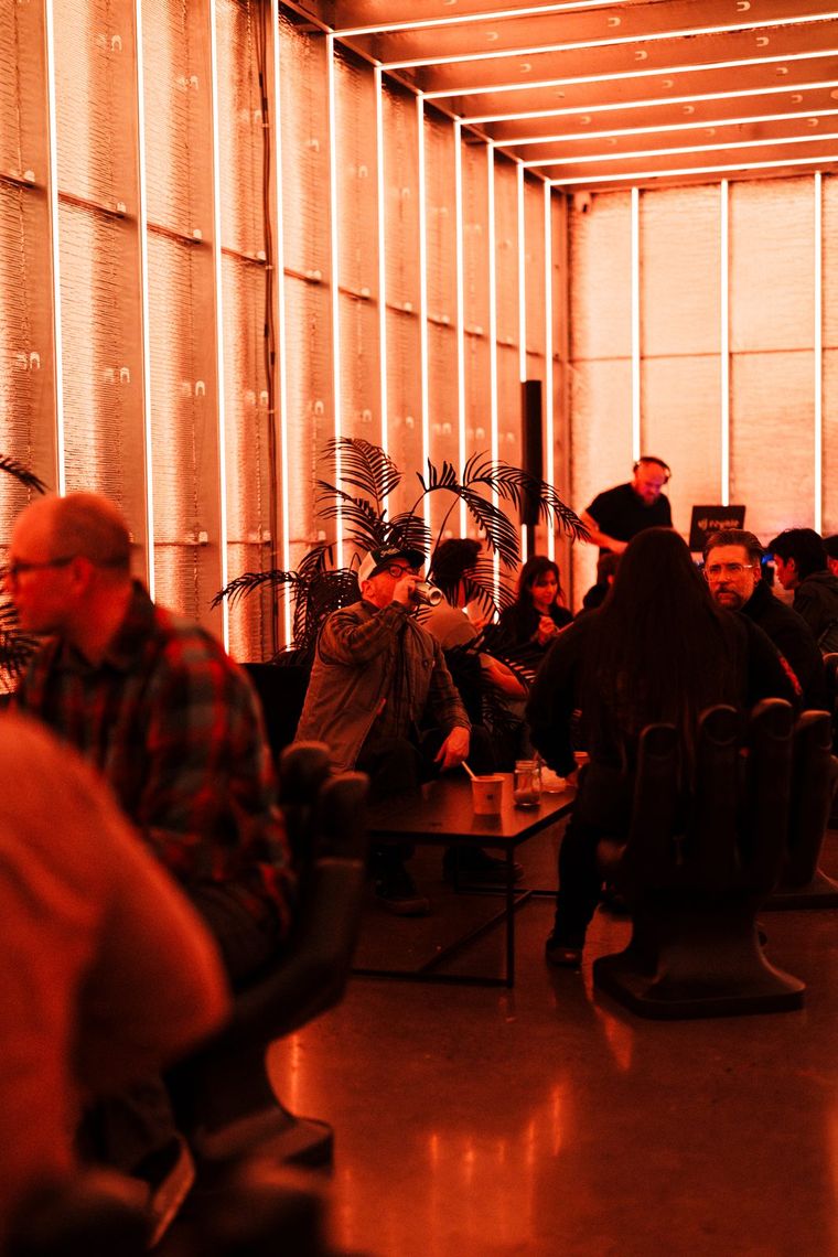 The Portland Lounge in warm orange light, guests seated at low tables among palms.