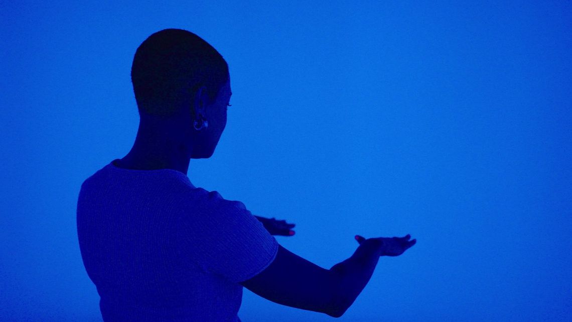 A guest holds an open hand out into the deep blue light.