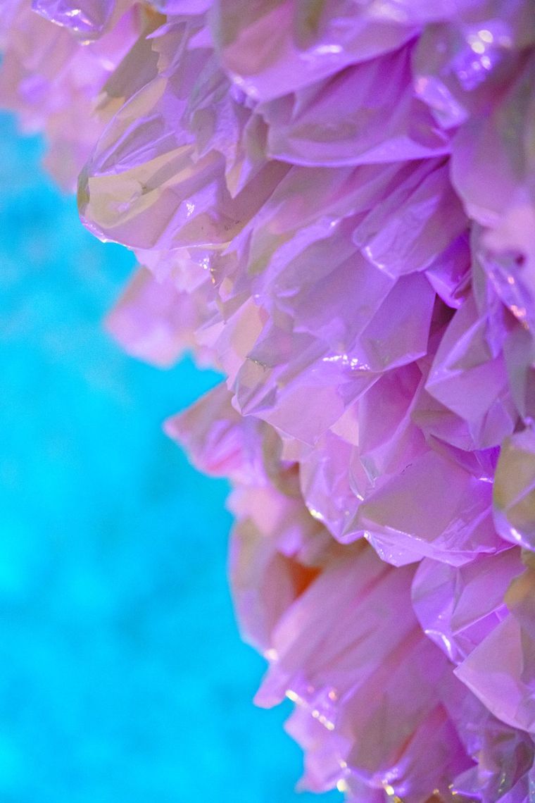 Close up of the crinkled plastic of Rainbow Cave, lit lilac against a soft turquoise glow.