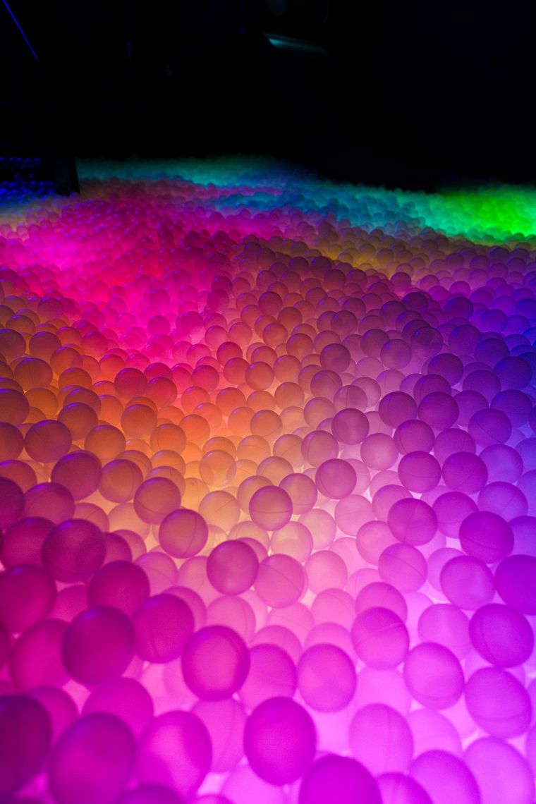 Translucent balls lit in a gradient of pink, orange and green across the pit.