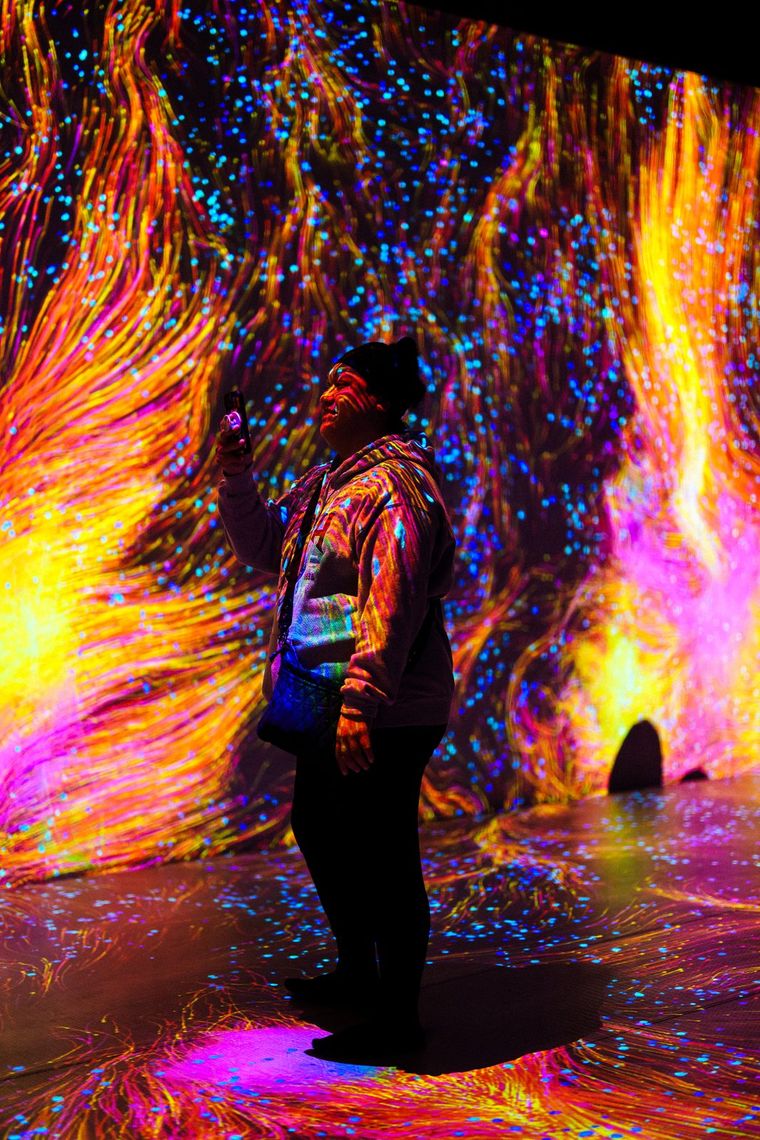 A guest looks up as orange and yellow light streams across every surface and the floor.