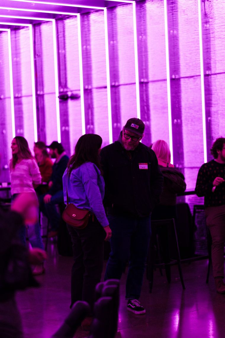 The Portland Lounge in magenta, guests gathered under rows of glowing vertical tubes.