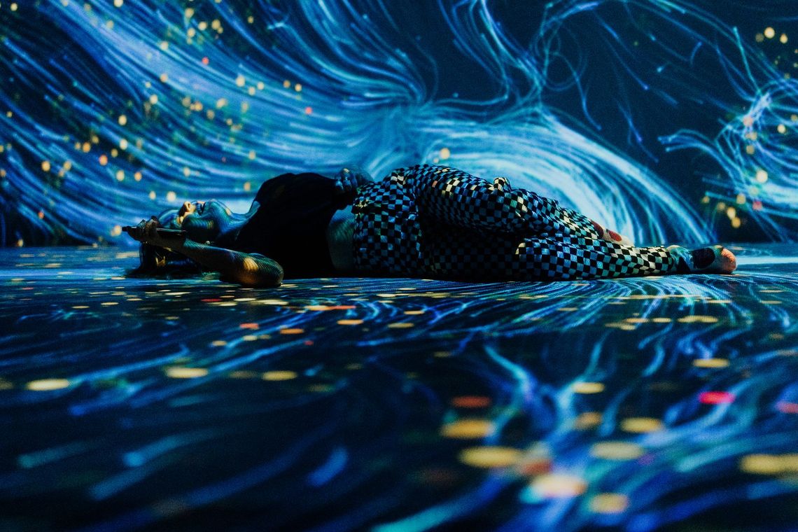 A guest lies on the floor as blue currents of light stream around them.