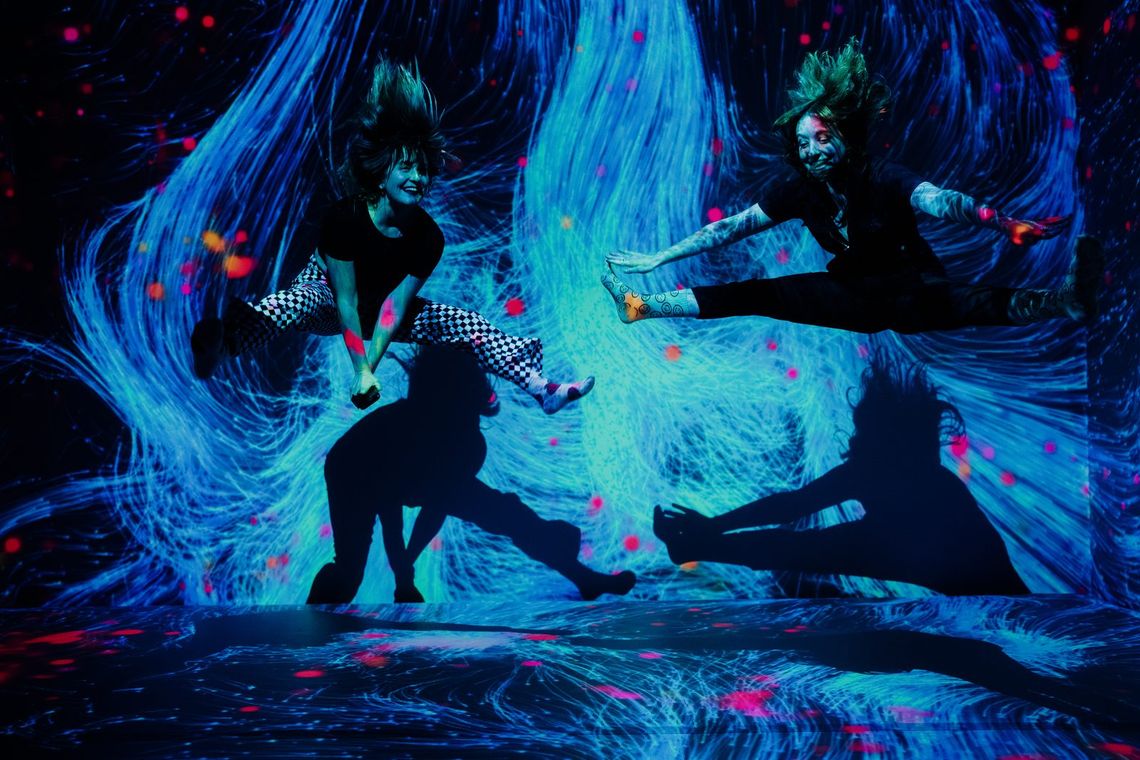 Two guests jump in midair facing each other, swirls of teal light behind them in Quantum Trampoline.