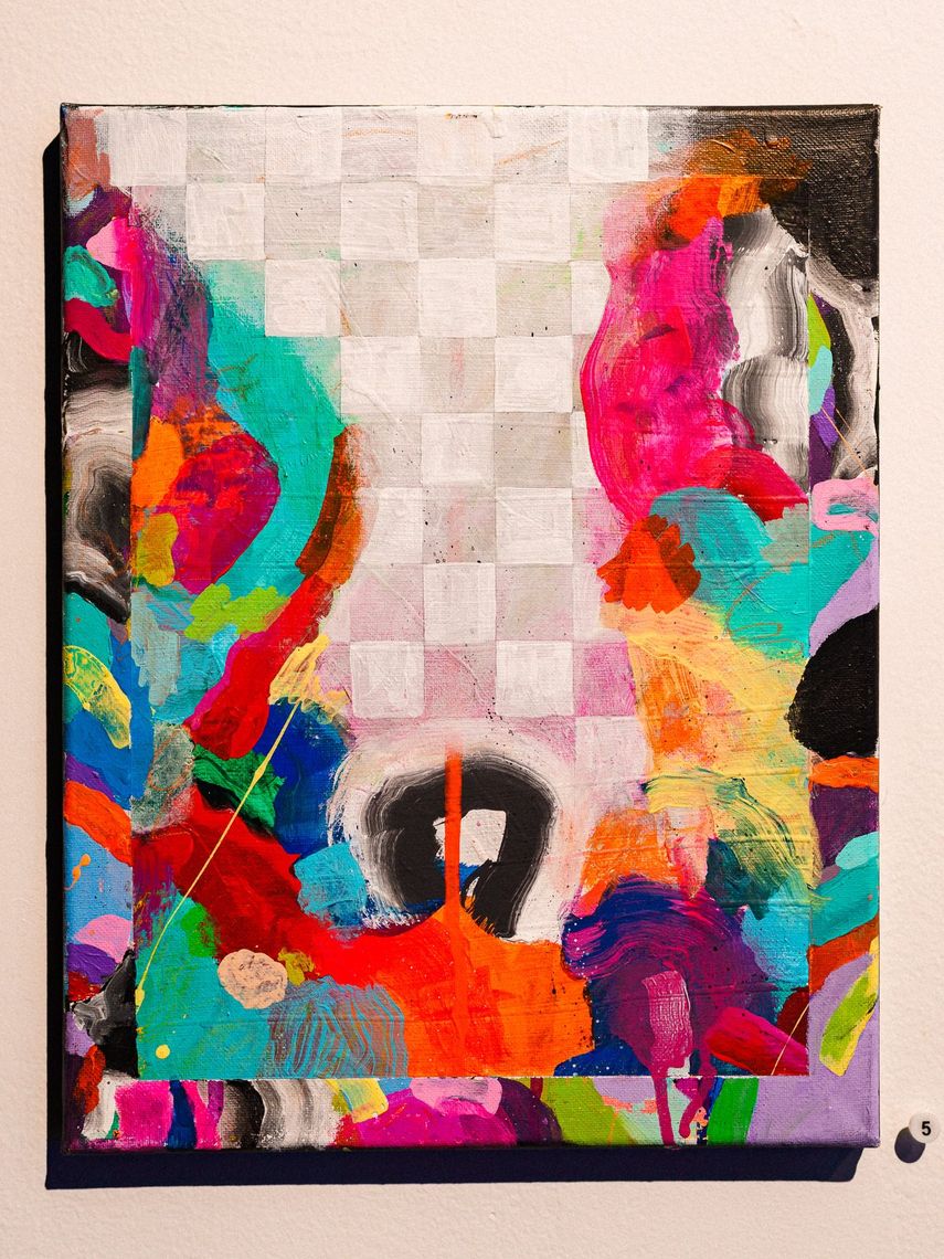 A painting with a white checkerboard running through bright pink, orange and teal shapes