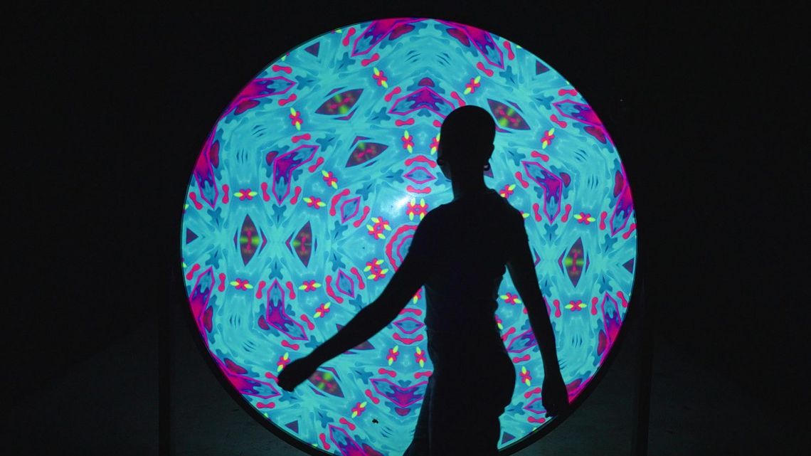 A silhouette walking across the Light Portal disc as it turns cyan and pink.