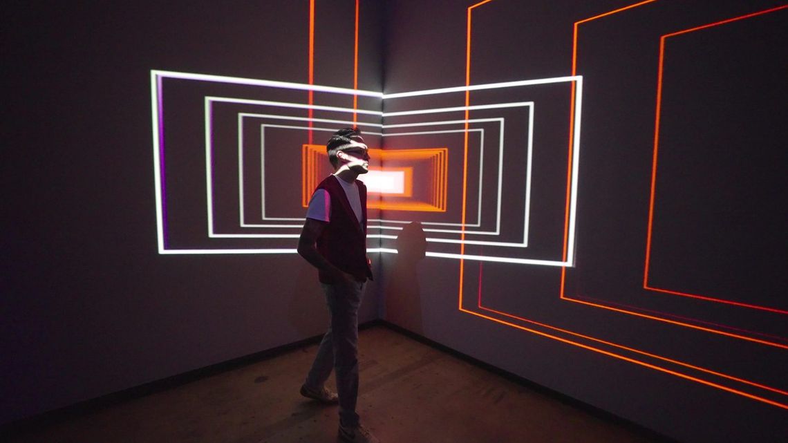 White nested frames projected across a dark corner of Onion Skin and across a guest walking through them.
