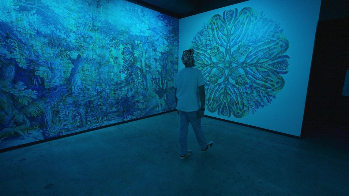 RGB in cyan light: a guest stands under the large medallion drawing beside the jungle mural.