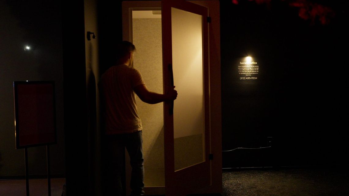 A guest opening the glowing door of the confession booth in the Secret Garden.