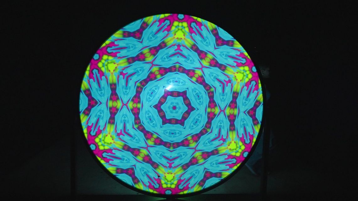 Light Portal's disc alone in the dark, a kaleidoscope of cyan, pink and lime.
