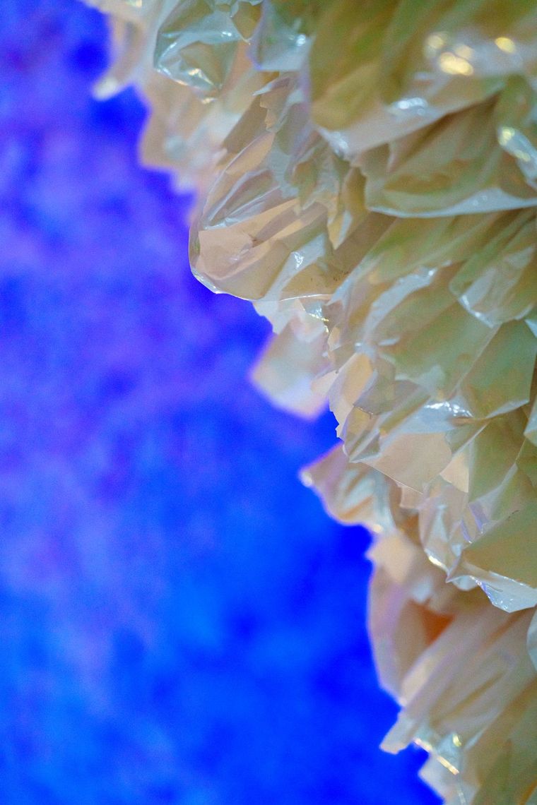 Close up of crinkled plastic bags in Rainbow Cave, gold against a deep blue glow.