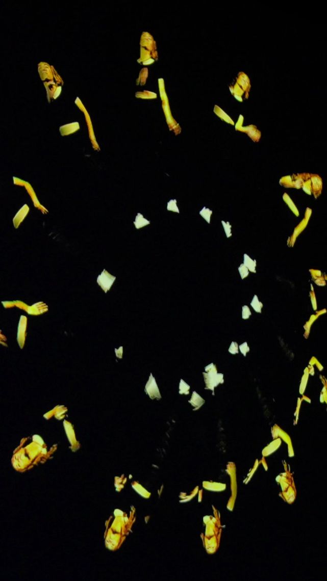 Gold hands and arms from the projection arranged in a kaleidoscope ring on black.