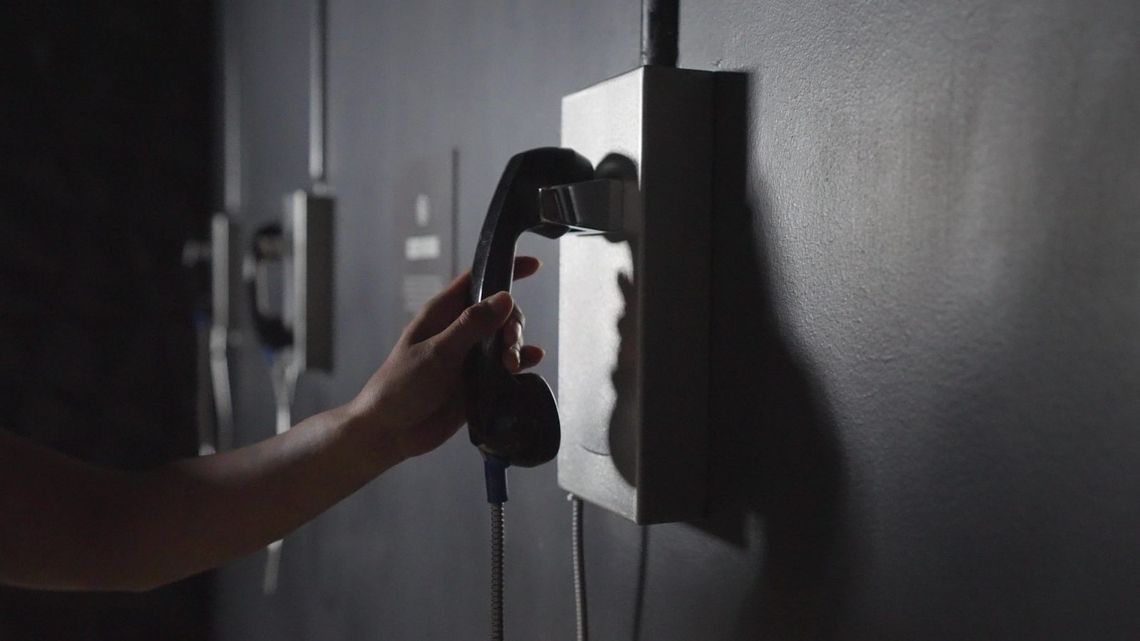 A hand reaches for the black receiver of a Secrets phone.