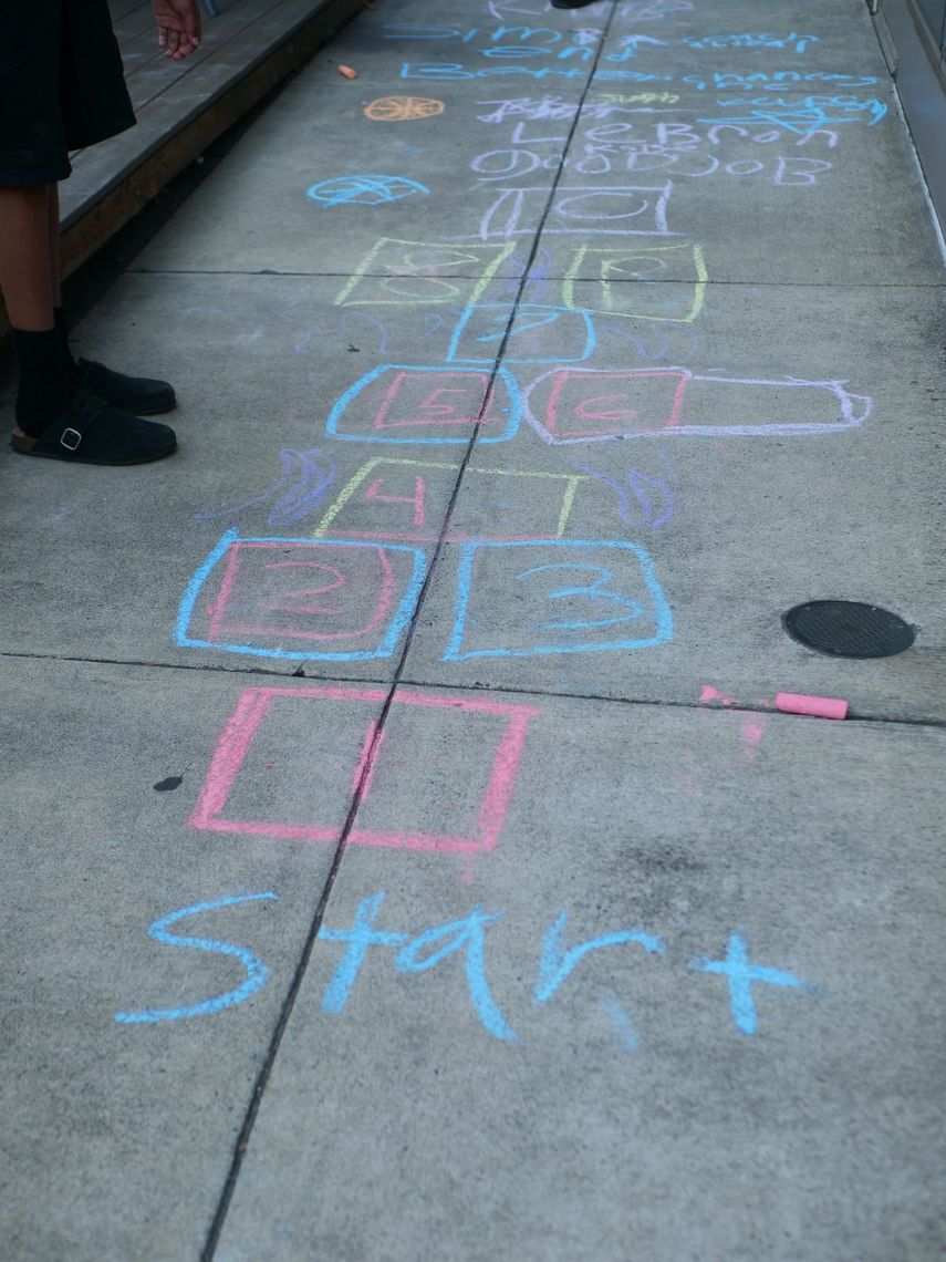 A chalk hopscotch grid drawn on a sidewalk with the word Start at the bottom