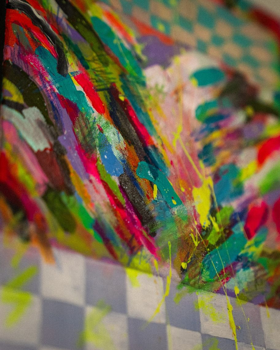 Close detail of an Ursula Zavala painting: thick strokes of pink, teal and yellow above a gray checkered band.