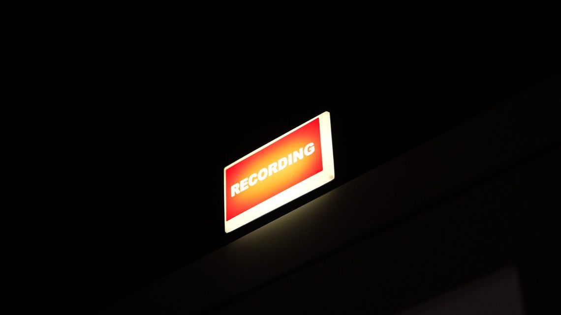 The red RECORDING light glowing above the booth door.